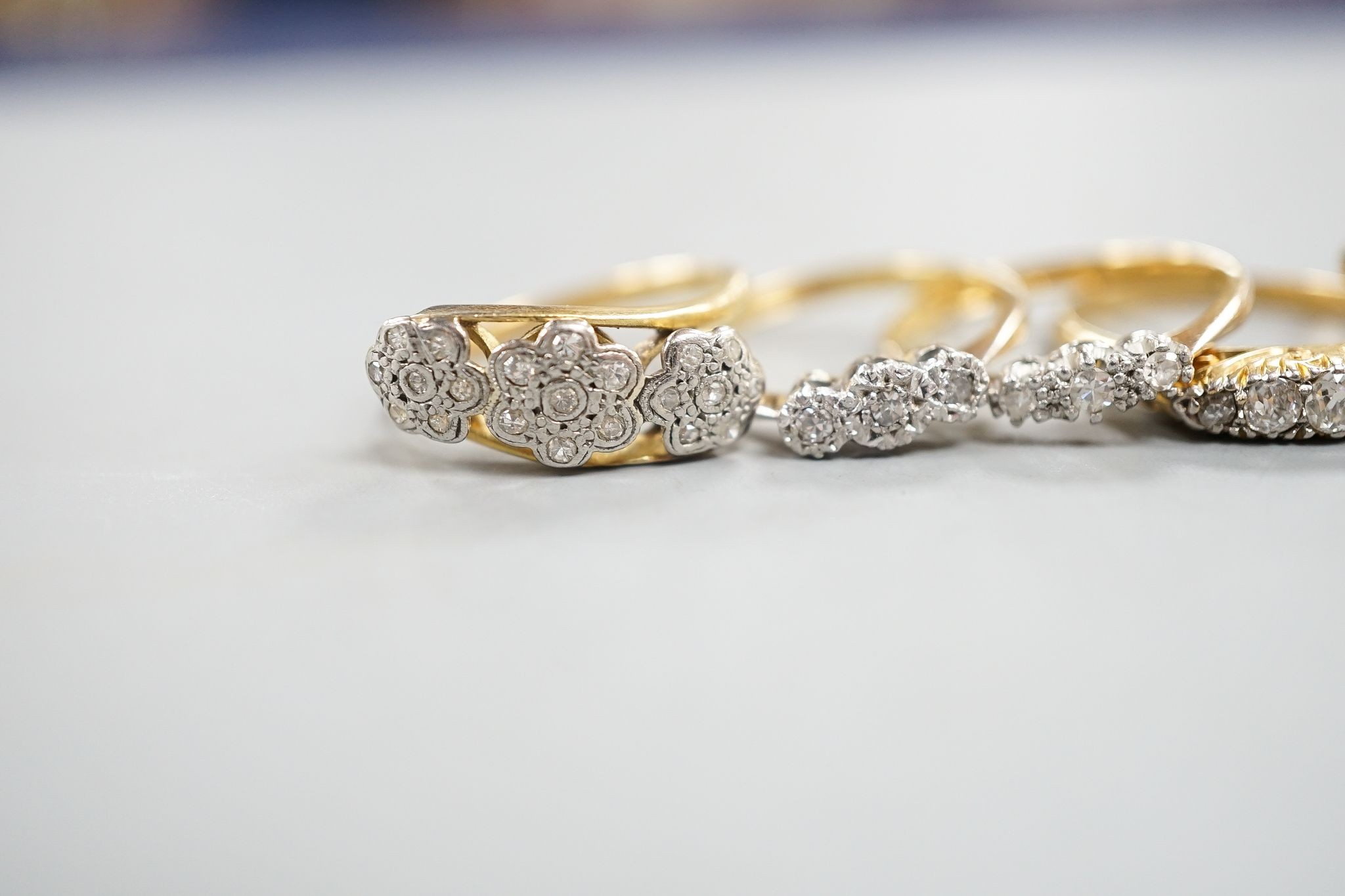 An early 20th century yellow metal and graduated five stone diamond set half hoop ring, size Q, gross 3.8 grams, three other 18ct and diamond chip set rings, gross 8 grams and a 9ct and diamond chip ring, gross 1.2 grams